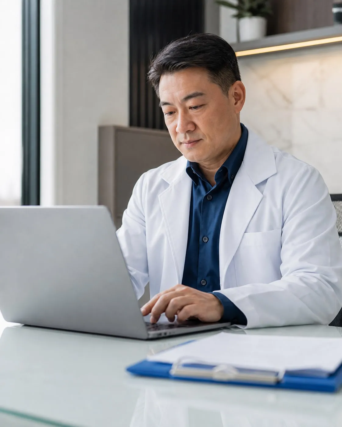 Médico de jaleco trabalha no notebook do consultório
